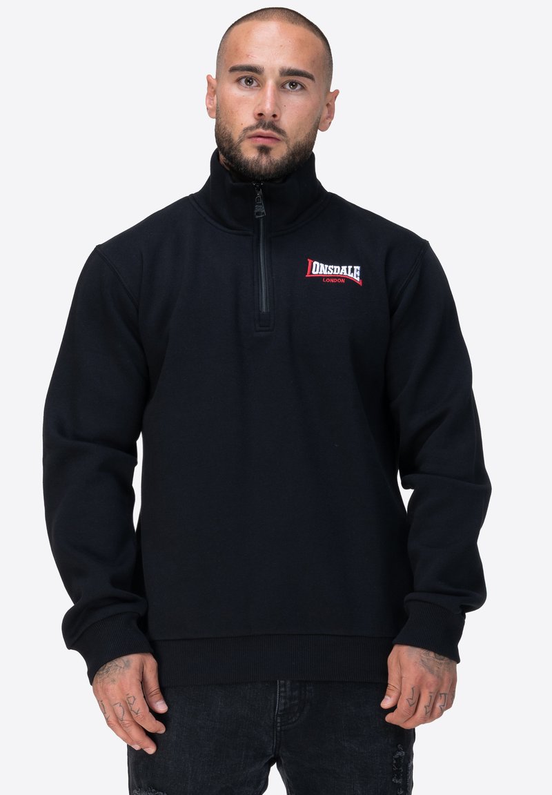 Felpa nera con zip e colletto alto. Presenta un logo Donsdale in rosso e un orlo e polsini a costine per un tocco di consistenza.