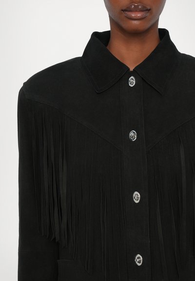 Giacca in suede nera con dettagli in evidenza di frange, colletto a punta e bottoni a pressione metallici sulla parte anteriore. Texture liscia e vestibilità strutturata.