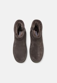 Bottines en suede marron avec fermeture éclair, doublure en fourrure douce et semelles en caoutchouc durables, présentant un design simple et fonctionnel.