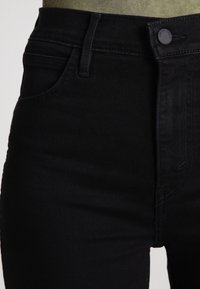 Högmidjade svarta denimjeans med en slät yta, standard femficksdesign och en enkel knappstängning med matchande midjeband.