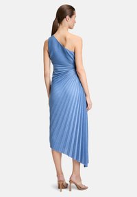 Asymetryczna niebieska sukienka z teksturowanymi fałdami, projekt z jednym ramieniem, długość do połowy łydki oraz lekko dłuższy tylny brzeg.