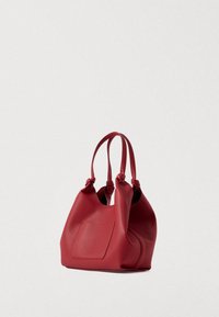 Rød læderhåndtaske med to håndtag og en ydre lomme, præsenteret mod en lys ensfarvet baggrund.