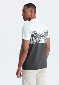 Pánské tričko s bílou horní polovinou s černým potiskem palmových listů a tmavě šedou dolní polovinou. Krátké rukávy a design s kulatým výstřihem.