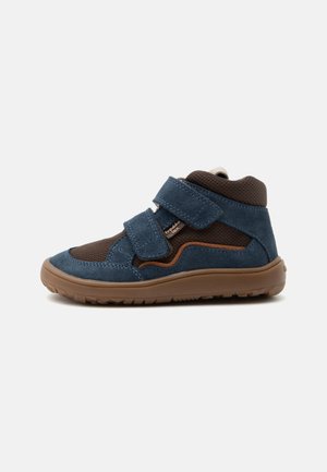 Basket montée enfant en bleu et marron avec deux bandes Velcro et une semelle en caoutchouc texturée.