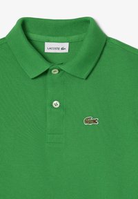 Polo verde con lavorazione a maglia testurizzata, dotato di colletto classico, due bottoni e un piccolo logo di coccodrillo ricamato sul petto.