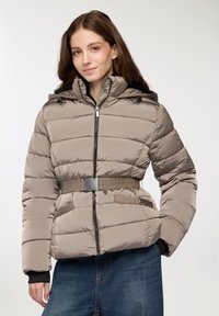 Giacca beige imbottita con cappuccio, dotata di zip frontale, vita con cintura e tasche laterali. Texture liscia con motivi a trapunta orizzontali.