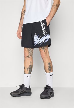 Svarte løpebukser med et hvitt og lyseblått grafisk mønster, kombinert med svarte sko og hvite sokker med Nike-logoen.