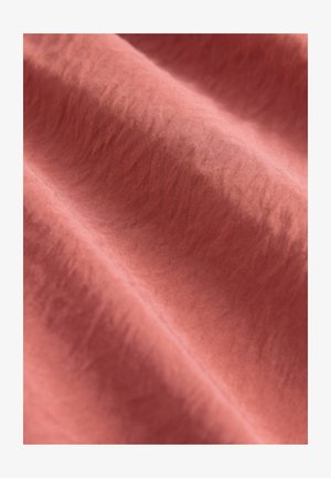 Pehme, tekstureeritud kangas tuhmikoral, õrendate voldide ja kortsudega, näidates siledat pinda ja peent sära.