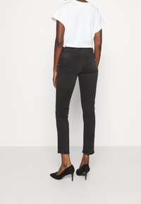 Mustat kapealahkeiset farkut, joissa on istuva malli, viisi taskua ja kevyt jousto. Yhdistetty mustien korkokenkien ja valkoisen t-paidan kanssa.