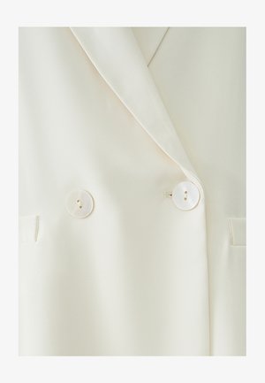Dvojradový blejzer v krémovej tkanine s hladkou štruktúrou, s dvoma veľkými, okrúhlymi, bielymi gombíkmi a bočnými vreckami.