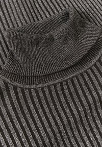 Maglione a collo alto a coste in nero con fili argentati. Presenta un colletto ripiegato e strisce verticali di diverse larghezze. Morbida texture.