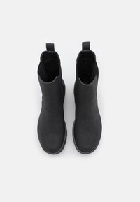 Botines negros de tobillo hechos de cuero suave, con un diseño minimalista sin hardware ni patrones visibles, y con una puntera redondeada.