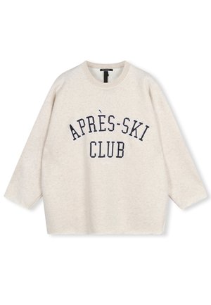 Pull beige clair à manches longues avec texte noir "APRÈS-SKI CLUB" imprimé sur le devant, avec un col rond et une coupe décontractée.