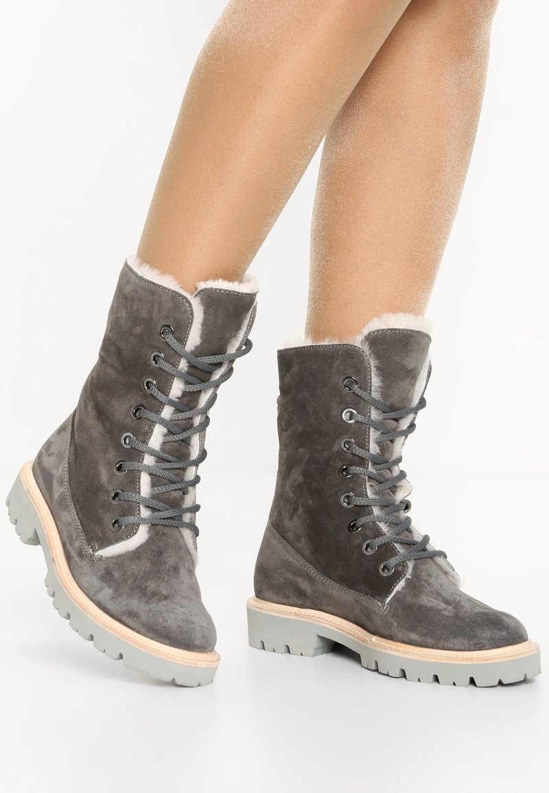 Stivaletti alla caviglia in suede grigio con bordo in pelliccia e lacci grigi, caratterizzati da una suola in gomma robusta e un midsole beige.