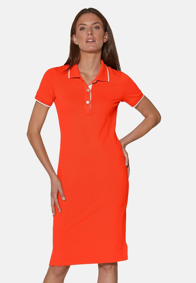 Polo-Kleid aus leuchtend orangefarbenem Stoff. Es hat kurze Ärmel, einen Kragen mit weißem Saum und eine dreiknöpfige Knopfleiste. Knielanger Schnitt.