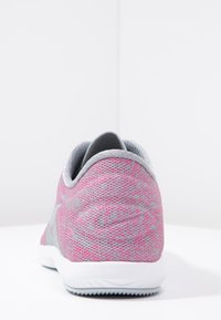 Scarpa sportiva rosa con un'esterno in maglia testurizzata, dettagli grigi e punta arrotondata. Presenta una suola in gomma bianca con motivi di aderenza.