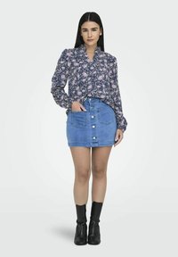 Blå denim mini kjol med framfickor och fem knappar. Blus med långa ärmar i blommönster i marinblå och rosa. Svarta ankelstövlar.