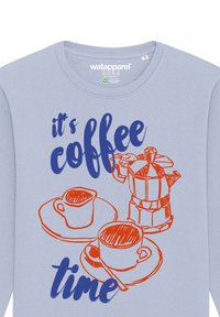 Une chemise à manches longues bleu clair arbore un texte graphique en rouge et bleu "c'est l'heure du café" avec une cafetière illustrée et des tasses.