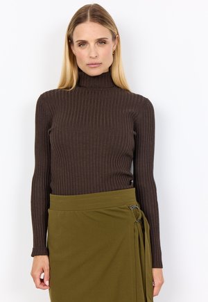 Brown ribbed turtleneck sweater paired with a green wrap skirt featuring a side ring detail. Fitted design with long sleeves and minimal texture.