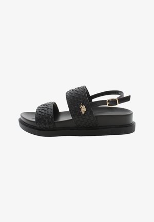 Schwarze gewebte Sandalen mit zwei breiten Riemen, strukturierter Oberfläche, flacher Sohle und einem goldenen Logo-Akzent. Verstellbarer Riemen hinten für einen sicheren Sitz.