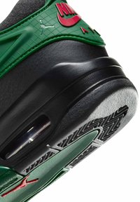 Grüne und schwarze Sneaker mit einem strukturierten grünen Obermaterial, rotem Nike-Logo, sichtbarem Air-Element und schwarzer Gummisohle mit einem Profilmuster.