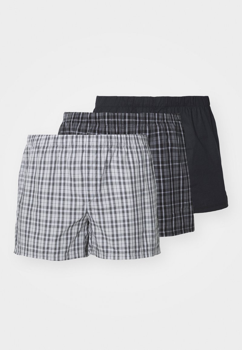 Tres pares de calzoncillos de hombre: uno con cuadros grises, otro con cuadros negros y uno negro liso; todos con cinturillas elásticas y de material de algodón.
