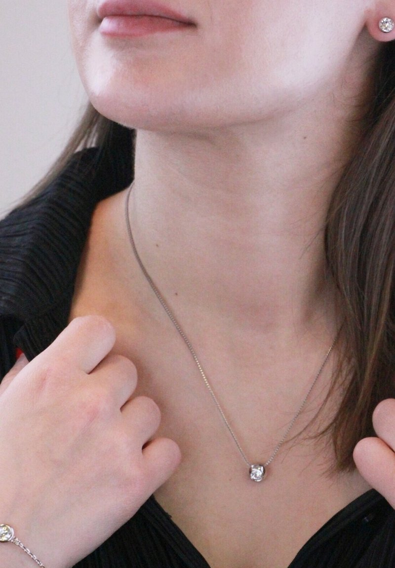 Collana in argento sterling con un pendente centrale in gemma trasparente, abbinata a una catena sottile. Bracciale in argento coordinato con un dettaglio in gemma simile.