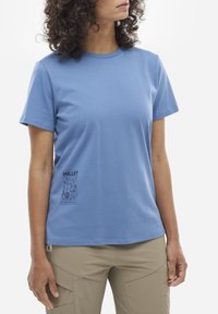 Jasnoniebieski t-shirt z krótkim rękawem wykonany z miękkiego materiału, z małym nadrukiem po lewej stronie oraz napisem "MILLET" poniżej.