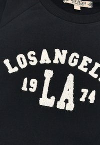 Schwarzer Sweatshirt mit kuscheligen weißen Aufdruck „LOS ANGELES 74“ und „LA“ mit rundem Ausschnitt und gerippten Bündchen. Aus weichem Baumwollmix.