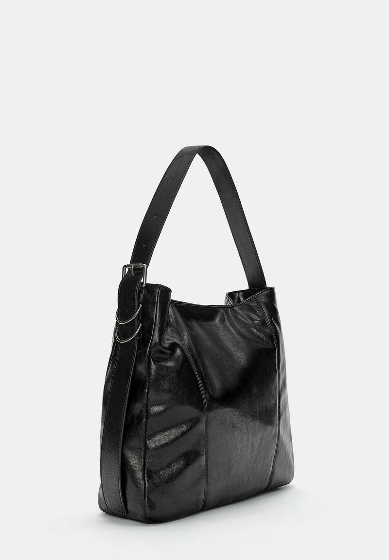 Bolso de hombro de piel negra con una correa ancha, hebilla de metal y un acabado suave, ligeramente brillante.