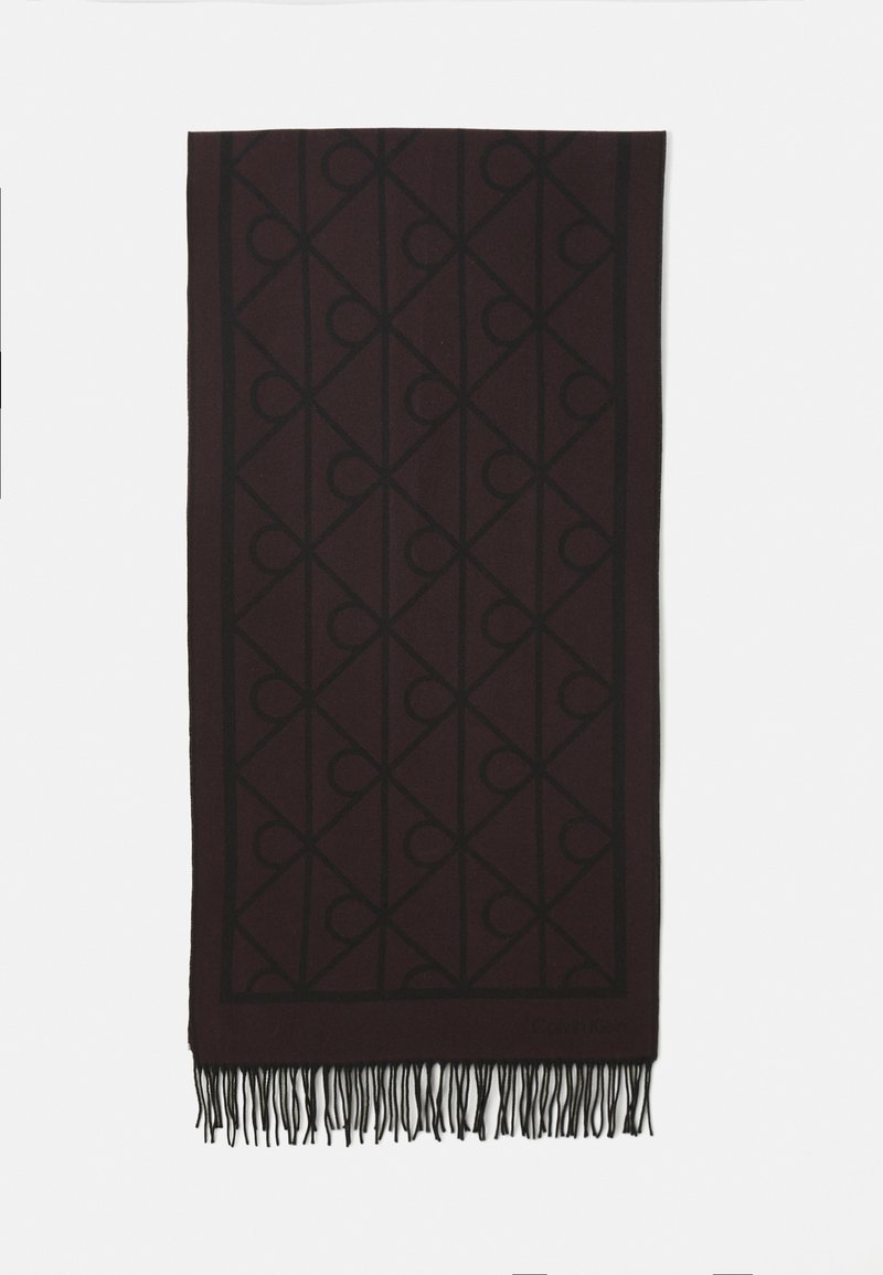 Mørk maroon rektangulært tørklæde med et sort geometrisk mønster, frynset kanter og et diskret "Calvin Klein" logo nær nederste hjørne.