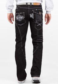 Jeans in denim nero con cuciture bianche e motivi ricamati decorativi sulle tasche posteriori. Presentano una vestibilità slim e un design a cinque tasche.