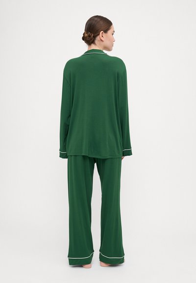 Green pajama set in lightweight fabric features a long-sleeve top with a collar and pants with white accents at the cuffs. Smooth texture.