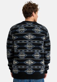 Sweater de malha em preto com padrão de diamante em cinza e azul. Gola redonda, mangas longas, punhos e bainha canelados. Textura suave.