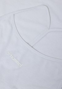 Vitt atletiskt linne gjort av mesh-material, med en dubbelremdesign och en liten präglad logotyp fram.