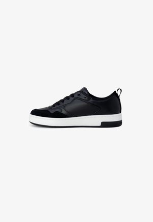 Czarny niski sneaker z wiązaniem na sznurówki, gładkimi i zamszowymi panelami, białą grubą gumową podeszwą oraz pętelką na pięcie.