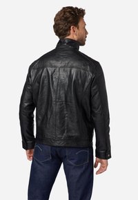 Zwarte leren jas met een hoge kraag, gladde textuur en gedetailleerde stiksels. Draag deze met donkerblauwe jeans, wat een casual uitstraling geeft.