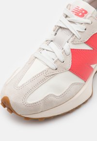 Sneaker med en krämfärgad överdel, rosa läderdetalj och grå mocka. Har vita snörningar och en strukturerad gummisula.