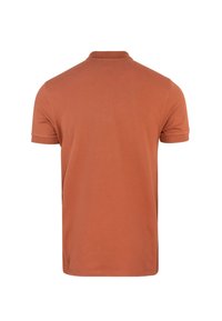 Polo a maniche corte di colore ruggine con colletto classico, realizzato in morbido cotone; presenta una consistenza liscia e un design minimalista.