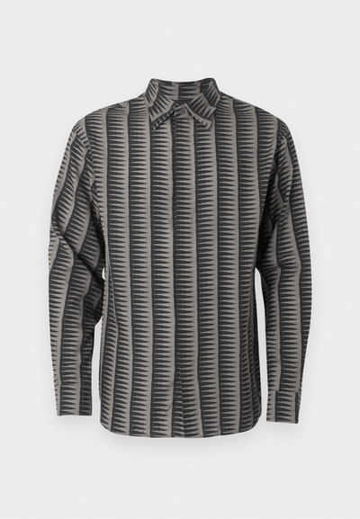 Πουκάμισο μακρύ μανίκι με κάθετες ζικ-ζακ ρίγες σε γκρι και μαύρο, με μυτερό γιακά και μανσέτες με κουμπιά σε λευκό φόντο.