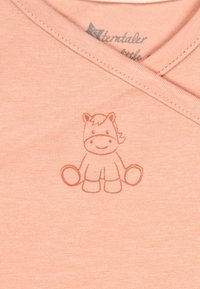 Light pink baby garment with a smiling cartoon horse printed in simple line art on the fabric near the neckline.