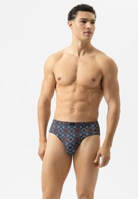 Heren zwembroek in de vorm van een slip met een marineblauwe basis en rode en blauwe bloemenprints, elastische tailleband en een strakke pasvorm. Gemaakt van rekbaar materiaal.
