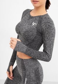 Gray long-sleeve athletic top with textured fabric and thumbholes, paired with matching high-waisted leggings featuring "SQUAT" text detail.