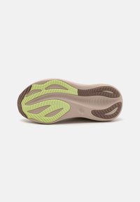 Suela de zapato con una base de color marrón claro, con acentos de goma verde y patrones texturizados para un mejor agarre. Acabado suave con un diseño de perfil distintivo.