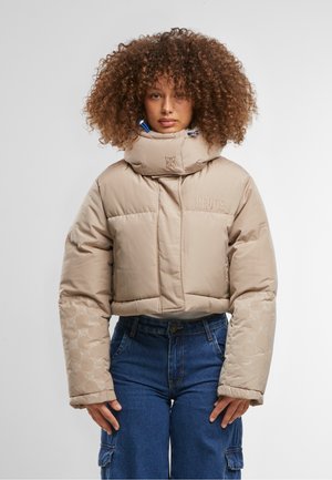 Beige cropped pufferjakke med høj krave, teksturerede ærmer med mønster, lynlås foran og broderet logo detalje.