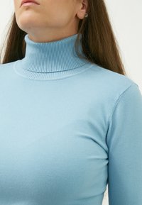 Hellblauer, gerippter Rollkragenpullover mit enganliegender Passform. Weicher Stoff mit hochgeschlossenem Kragen und glatten Ärmeln. Schlichtes Design ohne Muster.