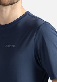 Námořnické modré sportovní tričko s kulatým výstřihem, krátkými rukávy a diskrétním logem "ROSSIGNOL" na hrudi. Hladká textura.