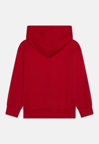 Felpa rossa con un grande cappuccio attaccato. Realizzata in tessuto morbido, presenta polsini e orlo a coste. Texture liscia, senza motivi né abbellimenti.