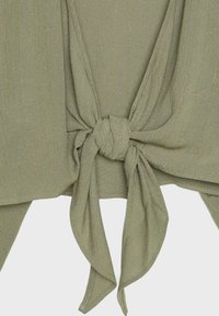 Gros plan d’un tissu vert olive noué avec une couture verticale discrète, créant un effet texturé et drapé.