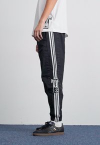 Melni sporta bikses ar trim baltām svītrām gar sāniem, ar Adidas logotipa uzlīmi kreisajā kājā. Izgatavotas no gludas auduma.